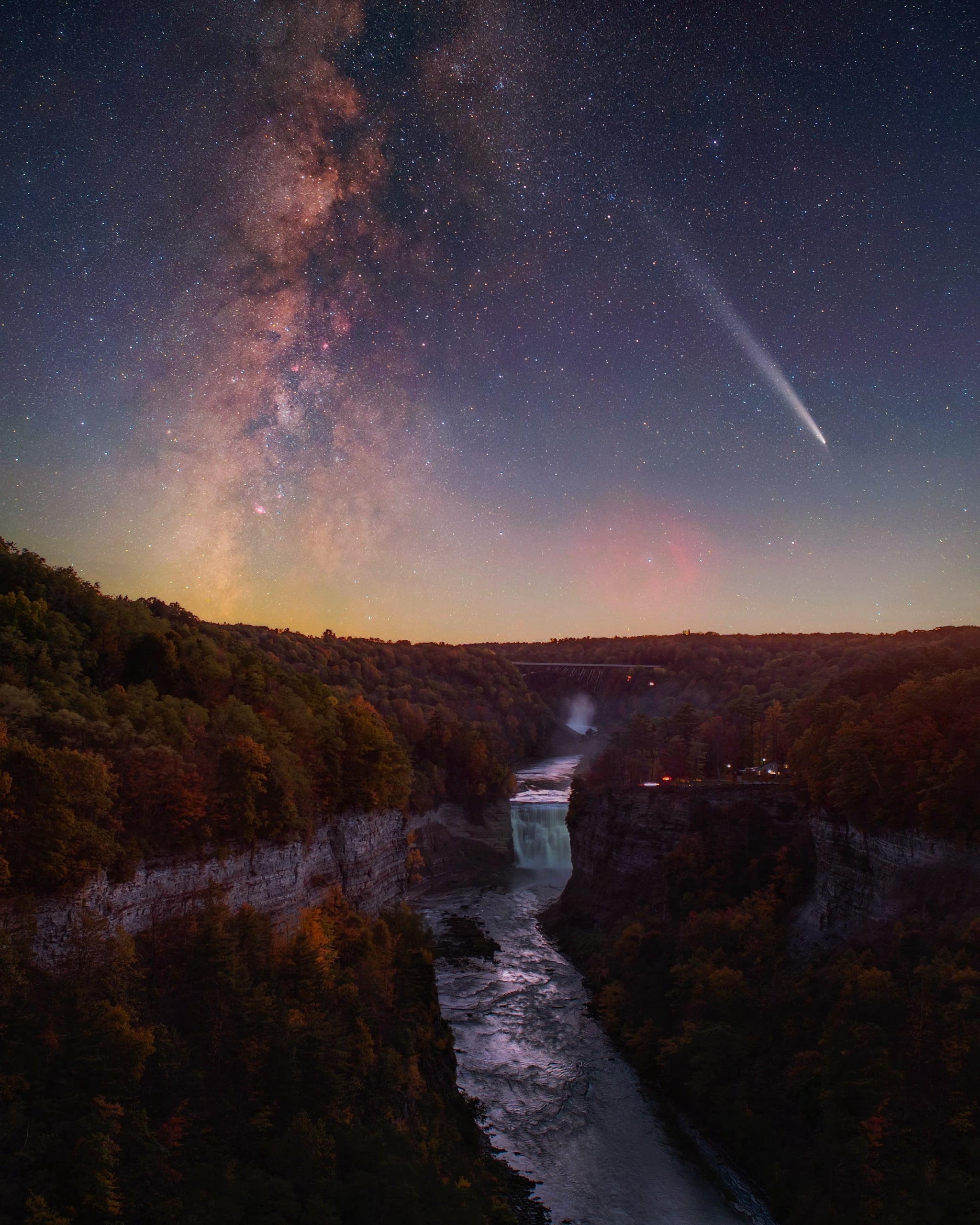The Milky Way stretches over a river and waterfall, illuminating the night sky with its celestial beauty.