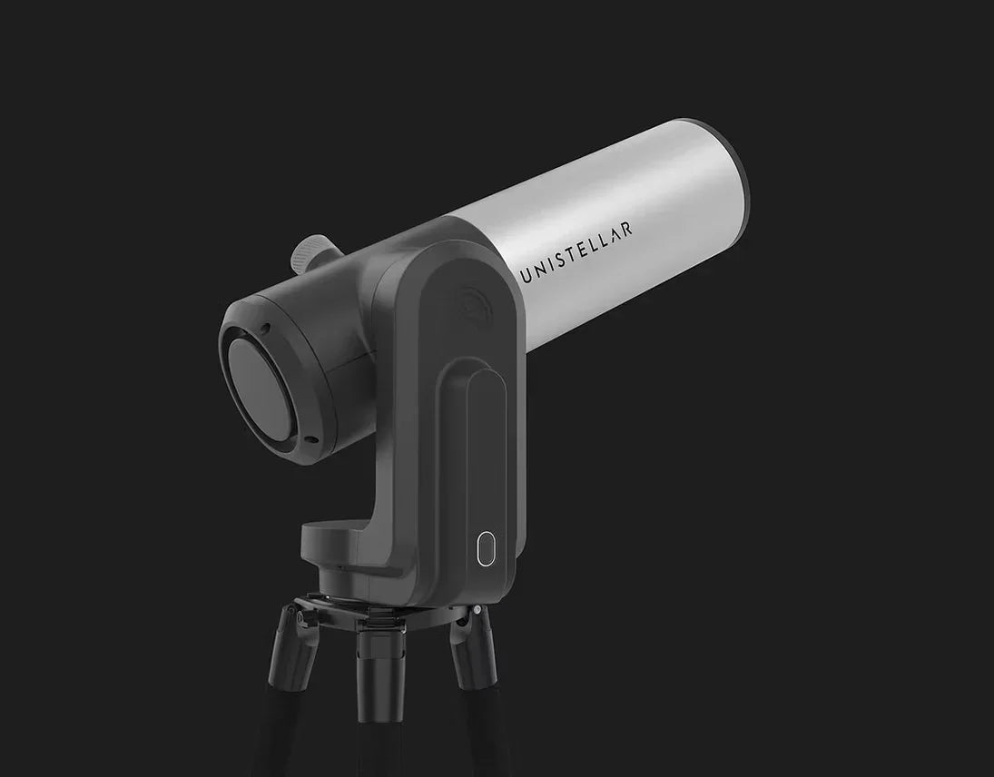 A reflector telescope positioned on a tripod, with a stark black background that accentuates its form and functionality.